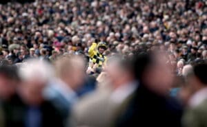 Jockey celebrates winning at Cheltenham in the middle of crowds of people