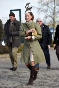A woman walking to Cheltenham in a tweed coat.