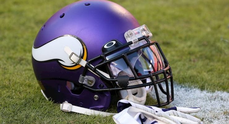 Minnesota Vikings NFL helmet on the grass next to gloves.